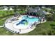 Community pool featuring a water slide, surrounding lounge chairs, umbrellas, and lush palm trees at 6563 Ryestone Way, Wesley Chapel, FL 33545