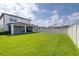 Large backyard with white fence, lush green lawn, and a covered patio at 6563 Ryestone Way, Wesley Chapel, FL 33545