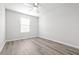 Neutral bedroom with fan, window, and wood-look flooring, offering a bright and airy space at 6563 Ryestone Way, Wesley Chapel, FL 33545