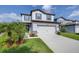Charming two-story home with a two-car garage, light gray siding, and a beautifully landscaped front yard at 6563 Ryestone Way, Wesley Chapel, FL 33545