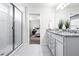 A bathroom displays a walk-in shower and a double sink vanity with granite countertops at 6563 Ryestone Way, Wesley Chapel, FL 33545