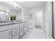 A bathroom displays a double sink vanity, granite countertops, and a walk-in shower at 6563 Ryestone Way, Wesley Chapel, FL 33545
