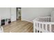 Bedroom features hardwood floors, a white crib, and a view into the bathroom at 707 9Th Sw Ave, Ruskin, FL 33570