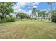 Sprawling backyard featuring lush green grass, mature trees, a waterfront, and a dock with plenty of space to enjoy the outdoors at 707 Warren Rd, Lutz, FL 33548