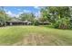 A lush green backyard with trees, beautiful lawn, and an enclosed porch on the back of the house at 707 Warren Rd, Lutz, FL 33548