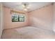 Cozy bedroom featuring a ceiling fan, neutral carpeting, and a window with garden views at 707 Warren Rd, Lutz, FL 33548