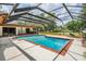 Enclosed pool area with a screened enclosure, a brick trimmed pool, outdoor seating, and beautiful greenery and trees at 707 Warren Rd, Lutz, FL 33548