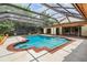 Enclosed pool area with a screened enclosure, brick trim, a diving board, outdoor seating, and beautiful trees at 707 Warren Rd, Lutz, FL 33548