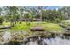 Lush backyard view with a wooden dock on the water, trees in the background, and a house in the distance at 707 Warren Rd, Lutz, FL 33548