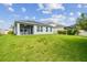 Wide view of the backyard showcasing a well-maintained lawn, covered patio, and neighboring houses beyond the fencing at 751 Cajeput Loop, Tarpon Springs, FL 34689
