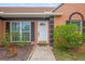 Close up of the front entrance with a white door, black shutters, and green flowered bushes at 7591 121St Ter, Largo, FL 33773