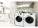 A well-organized laundry room with white washer and dryer, shelving, and a glimpse into the dining area at 7591 121St Ter, Largo, FL 33773