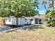 Inviting front exterior with mature trees offering shade, complemented by lush tropical landscaping, creating curb appeal at 829 Riverside Dr, Tarpon Springs, FL 34689