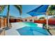 Backyard pool with a blue umbrella and gazebo, complemented by lush landscaping and a privacy fence at 829 Riverside Dr, Tarpon Springs, FL 34689