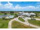 Aerial view of a clubhouse featuring a pool, golf carts, and manicured landscaping at 987 Chickadee Dr, Venice, FL 34285