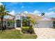 Charming home featuring lush landscaping, a barrel tile roof, and a brick driveway at 987 Chickadee Dr, Venice, FL 34285