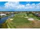 Aerial view of a golf course community with homes lining a scenic waterfront, and lush greenery at 987 Chickadee Dr, Venice, FL 34285