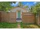 Backyard entrance with a wooden fence, green door, and landscaped surroundings at 1003 E Emma St, Tampa, FL 33603