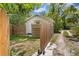 A cozy fenced backyard with wooden fence, compact storage shed, and lots of shade at 1003 E Emma St, Tampa, FL 33603