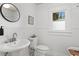 Charming bathroom with a pedestal sink, round mirror, and classic black and white tile floor at 1003 E Emma St, Tampa, FL 33603