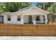 Charming white home featuring a covered porch, fresh paint, and stylish wood fence at 1003 E Emma St, Tampa, FL 33603