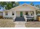 Charming bungalow featuring a teal front door, covered porch and well-maintained landscaping at 1003 E Emma St, Tampa, FL 33603