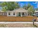 Charming bungalow featuring a teal front door, covered porch and a newly installed wooden fence at 1003 E Emma St, Tampa, FL 33603