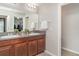 Well-lit bathroom featuring double sinks, granite countertops, wood cabinets and plenty of mirror space at 10104 Carloway Hills Dr, Wimauma, FL 33598