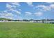 Wide open grassy field with houses and trees in the distance on a sunny day at 10104 Carloway Hills Dr, Wimauma, FL 33598