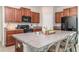 Well-lit kitchen with stainless steel appliances, wood cabinets, granite countertops and barstool seating at 10104 Carloway Hills Dr, Wimauma, FL 33598