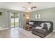 Cozy living room features tile floors, a ceiling fan, and sliding glass doors to the backyard at 10104 Carloway Hills Dr, Wimauma, FL 33598