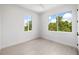 A bright bedroom with a ceiling fan, light floors and views of nature from two windows at 10340 2Nd N Way, St Petersburg, FL 33716