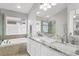 Elegant bathroom featuring double vanity, marble countertops, and a soaking tub with tile surround at 11324 Cypress Reserve Dr, Tampa, FL 33626