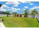 Expansive backyard featuring lush green lawn, tropical foliage, and a white fence overlooking a serene pond at 11612 Sunburst Marble Rd, Riverview, FL 33579