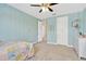 A well-lit bedroom features blue walls, carpeted floors, a ceiling fan, and a charming bed with a colorful quilt at 11612 Sunburst Marble Rd, Riverview, FL 33579