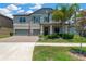 Charming two-story home featuring a brick driveway, manicured lawn, and inviting front porch with palm trees at 11612 Sunburst Marble Rd, Riverview, FL 33579