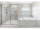 Bathroom featuring a glass shower and soaking tub with tile surround and a bright window at 11726 Sunburst Marble Rd, Riverview, FL 33579