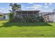Manicured backyard with a screened porch, tropical foliage, and a well maintained green lawn at 1175 San Carlos Ne Ave, St Petersburg, FL 33702