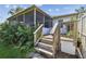 View of steps and screened porch in the backyard with green grass and lush landscaping at 1175 San Carlos Ne Ave, St Petersburg, FL 33702
