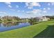 A tranquil backyard pond reflects the blue sky and clouds on a sunny day with well-manicured lawn at 1175 San Carlos Ne Ave, St Petersburg, FL 33702