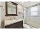 Bathroom with walk-in shower, dark vanity, stone countertop, and framed mirror at 1175 San Carlos Ne Ave, St Petersburg, FL 33702