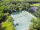 Aerial view of well-maintained tennis courts surrounded by lush greenery and a serene pond at 1175 San Carlos Ne Ave, St Petersburg, FL 33702