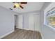 A bright bedroom with wood-look floors, a ceiling fan, a closet and a large window at 11809 129Th Ave, Largo, FL 33778