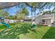 Spacious backyard with lush green lawn, mature trees, swing set, and covered patio perfect for outdoor activities at 11927 Steppingstone Blvd, Tampa, FL 33635