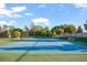 Outdoor tennis court with green and blue painted surface, surrounded by trees and netting, benches for spectators at 12170 Gothic Rd, Spring Hill, FL 34610
