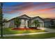 Inviting home with manicured lawn, landscape lighting and mulch beds under a vibrant twilight sky at 12653 Palapa Loop, Spring Hill, FL 34610