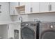 Well-equipped laundry room with gray front-load washer and dryer, white cabinets, and modern fixtures at 12653 Palapa Loop, Spring Hill, FL 34610