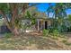 Quaint home featuring mature trees, lush tropical foliage, and a brick walkway at 1402 E Mohawk Ave, Tampa, FL 33604