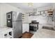 Updated kitchen featuring stainless steel appliances, white cabinetry, and decorative tile backsplash at 1402 E Mohawk Ave, Tampa, FL 33604