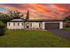 A well-lit home showcasing a manicured lawn, a dark driveway and accents, and a warm and inviting entrance at 1873 Murray Ave, Clearwater, FL 33755